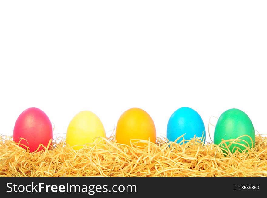 Five painted eggs on a straw on a white background