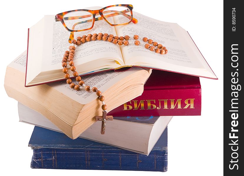 Open Holy Bible lying on stack of old books with glasses, cross and beads. Open Holy Bible lying on stack of old books with glasses, cross and beads