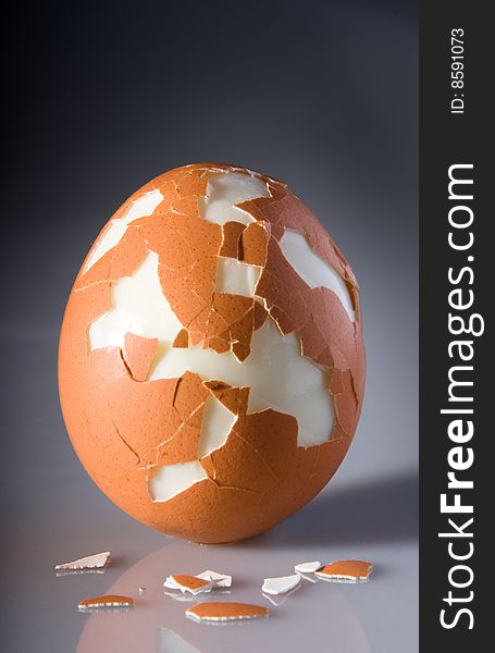 Single cracked egg isolated on dark background with reflected base and pieces of shell. Business concept for excessive stress. Single cracked egg isolated on dark background with reflected base and pieces of shell. Business concept for excessive stress.