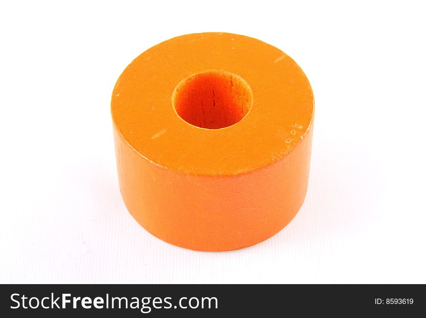 A cylindrical orange wooden toy brick with a hole in the middle. A cylindrical orange wooden toy brick with a hole in the middle