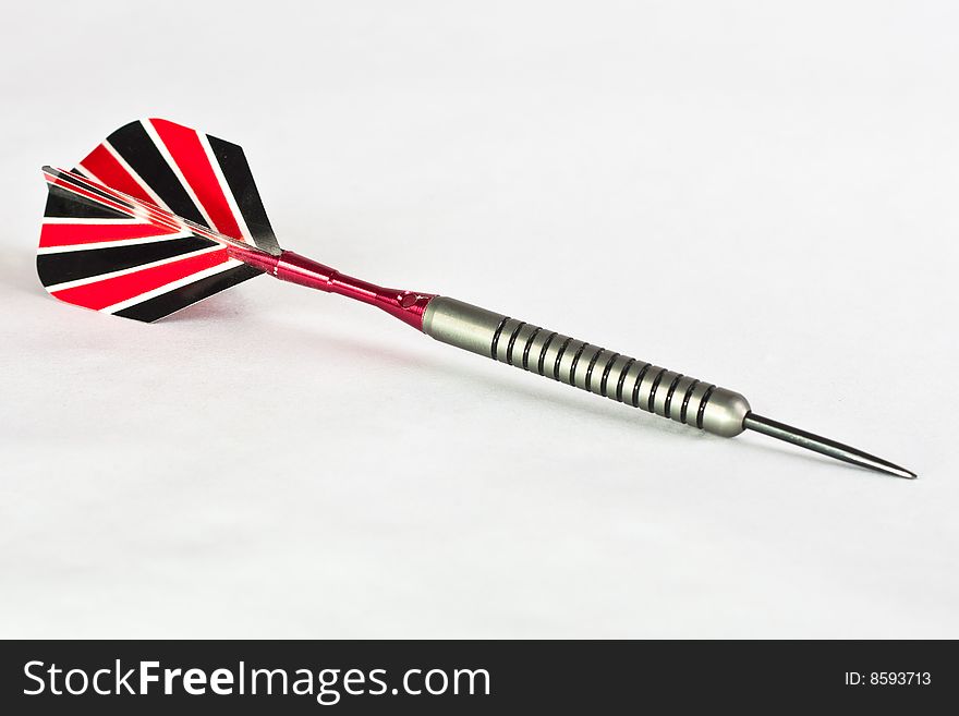 A single playing dart with a red white and black plastic feather and polished steel shaft