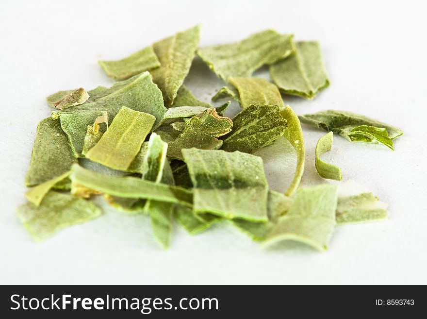 A macro shot of a pile of freeze dried tarragon against a white background