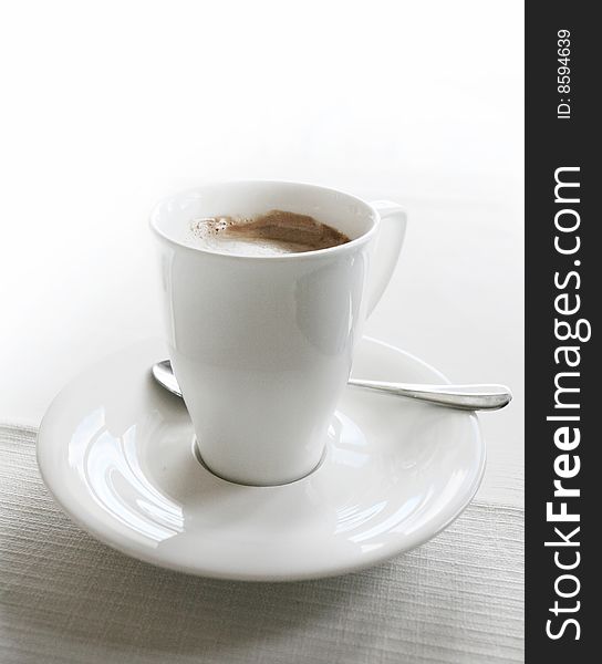 Coffee in white cup over white table. Coffee in white cup over white table