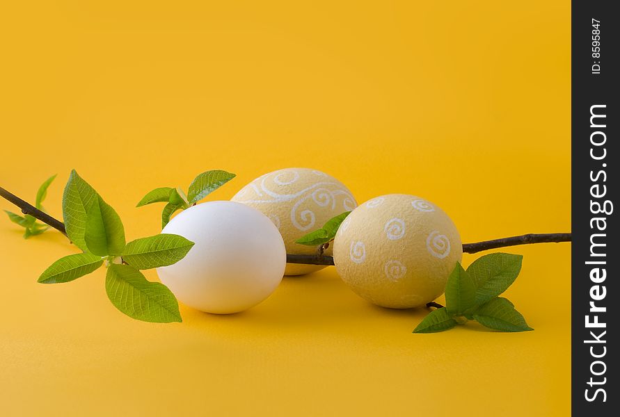 Easter eggs on a yellow background with a blossoming out sprig