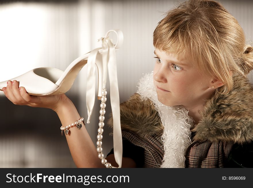 Cute young girl in dress-up clothes looking at a pointy shoe. Cute young girl in dress-up clothes looking at a pointy shoe