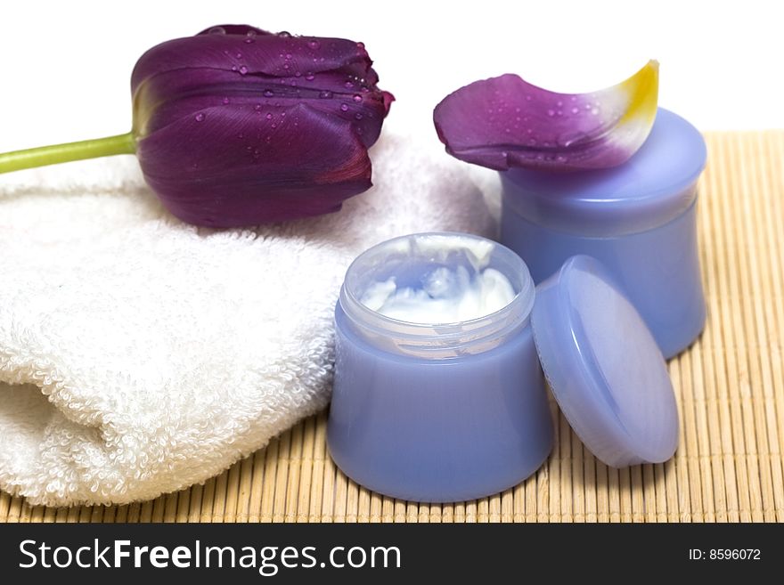 Spa essentials (cream, white towel and violet flower)