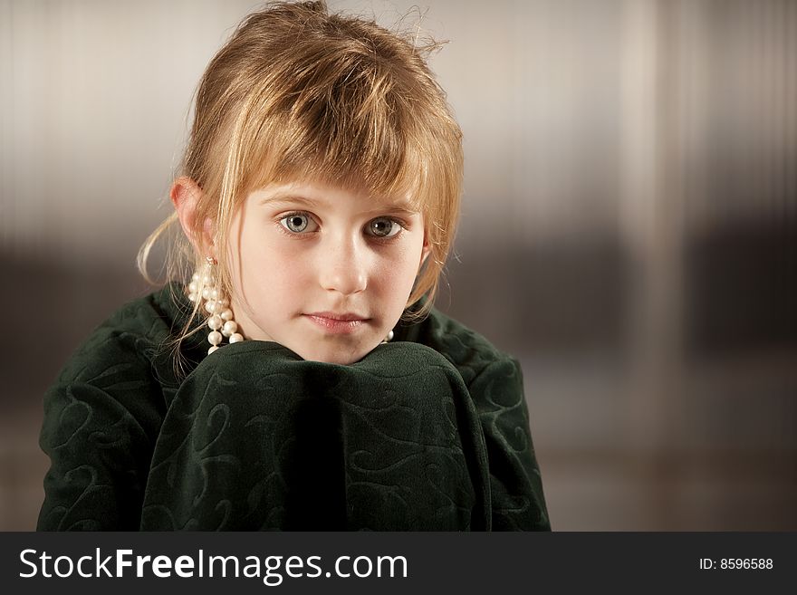 Cute young girl with big eyes in dress-up clothes chin on knees