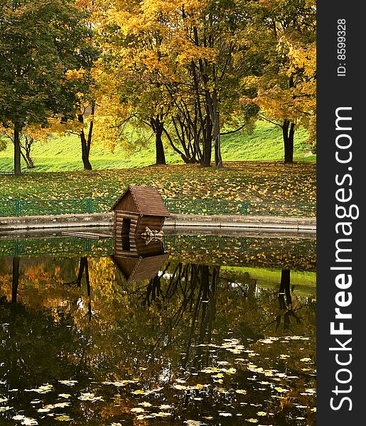 A park lake with a duck house on water. A park lake with a duck house on water