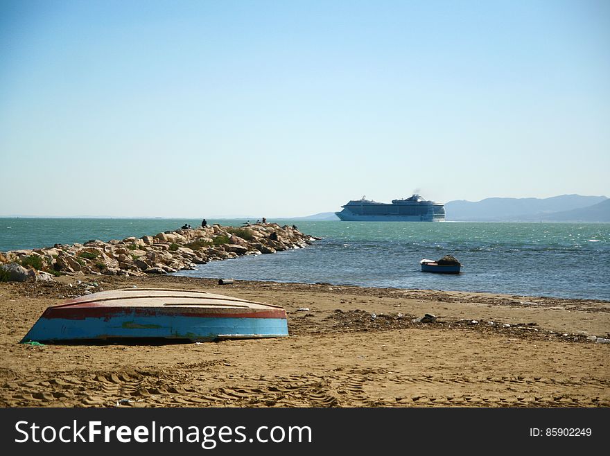 Blue, wooden boat, upside down, lying on an empty beach, by the sea