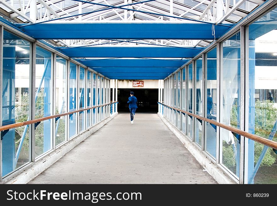 A teenager running through a glassed in overpass.