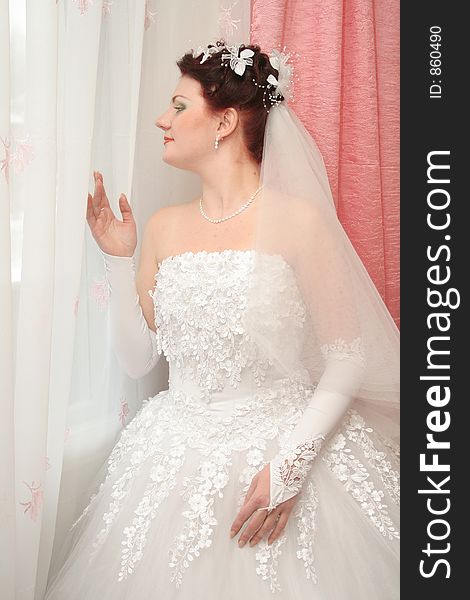 Bride stand beside window and looks at street