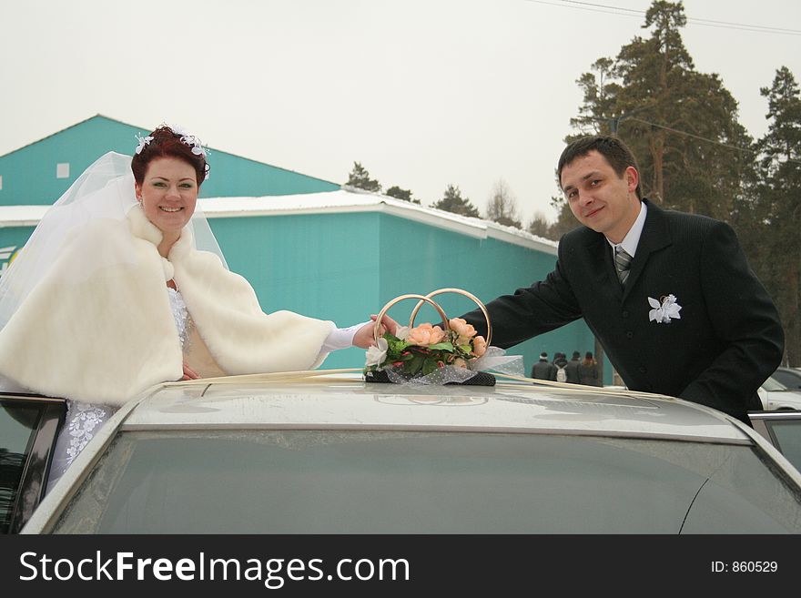 Bride and bridegroom are taken pictures beside car. Bride and bridegroom are taken pictures beside car