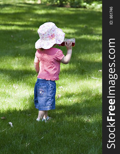 Toddler Girl wearing a large brim sun hat drinking a cup of juice on a warm summer day. Toddler Girl wearing a large brim sun hat drinking a cup of juice on a warm summer day.