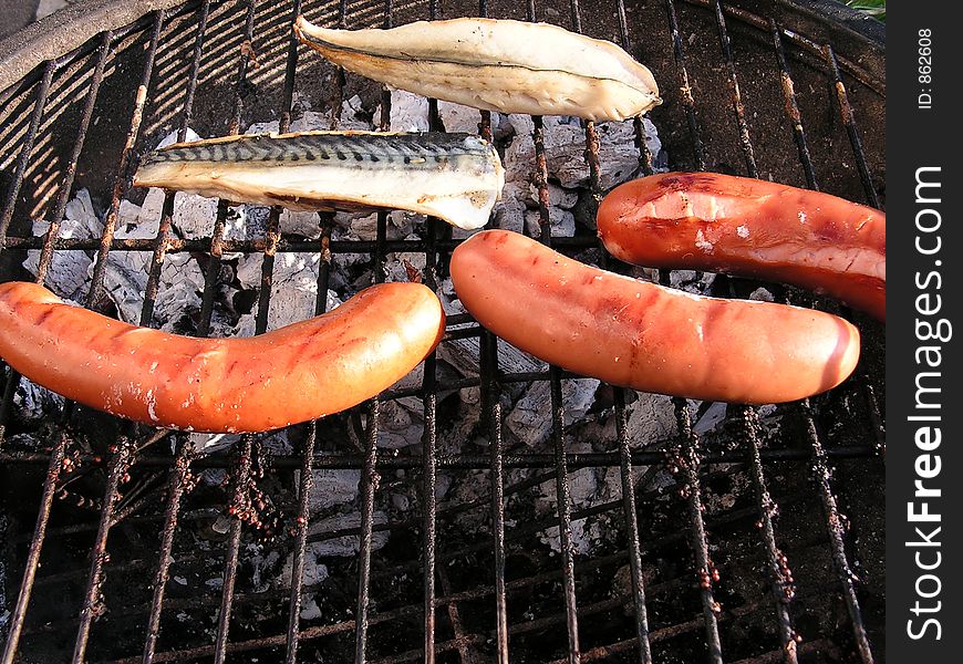 A barbecue with bratwurst and amoked mackeral.