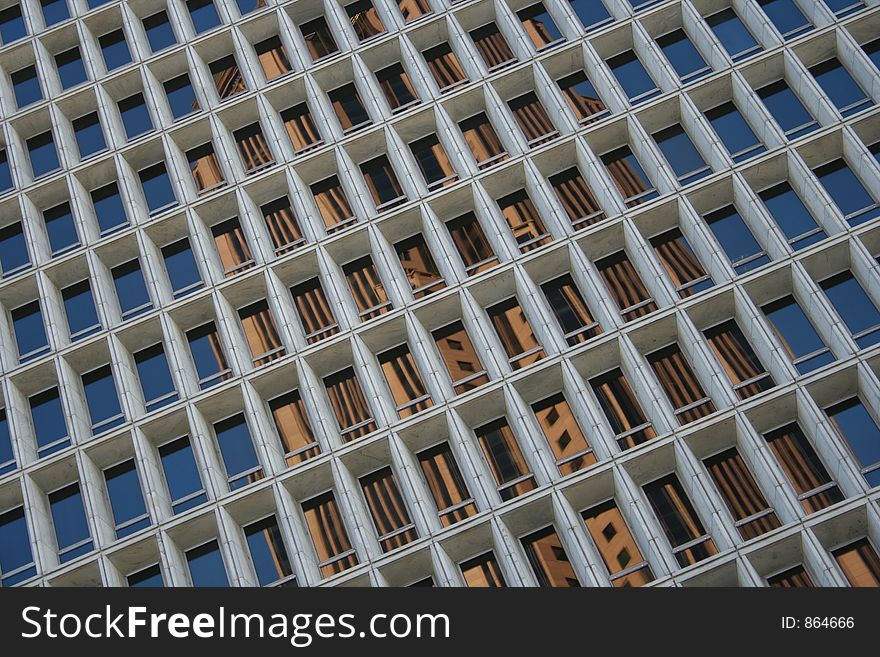 A building and the blue sky reflect off of rows of windows. A building and the blue sky reflect off of rows of windows.