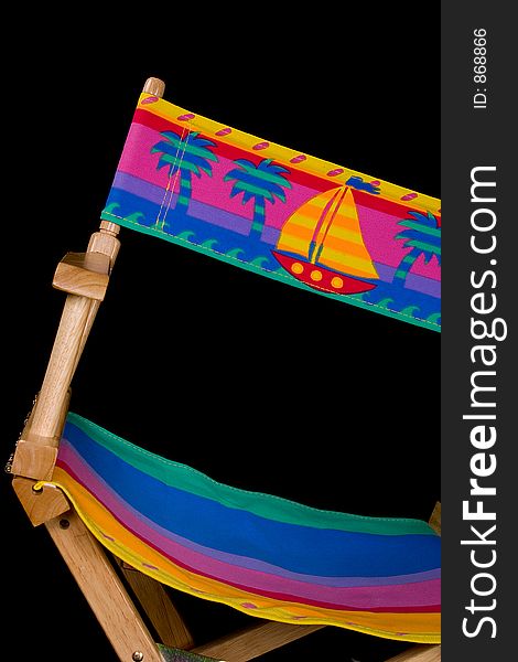 Multi-colored fold out wooden and cloth beach (patio) chair. Isolated on black. Multi-colored fold out wooden and cloth beach (patio) chair. Isolated on black.