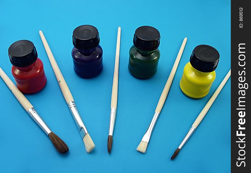 Brushes and bottles of paint on a blue bakcground. Brushes and bottles of paint on a blue bakcground