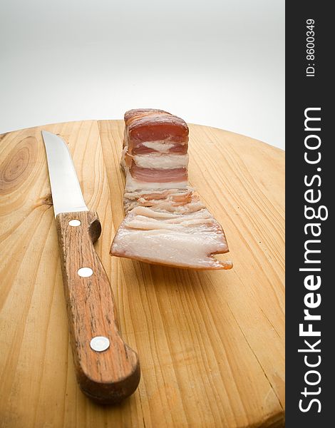 Bit ofbacon and knife on kitchen chopping board. Bit ofbacon and knife on kitchen chopping board