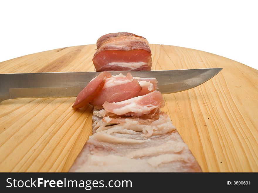 Knife cutting bacon on chopping board