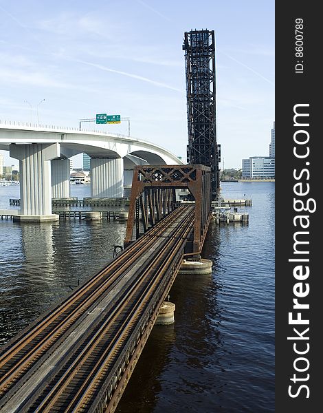 A railroad bridge over a river in a downtown area.