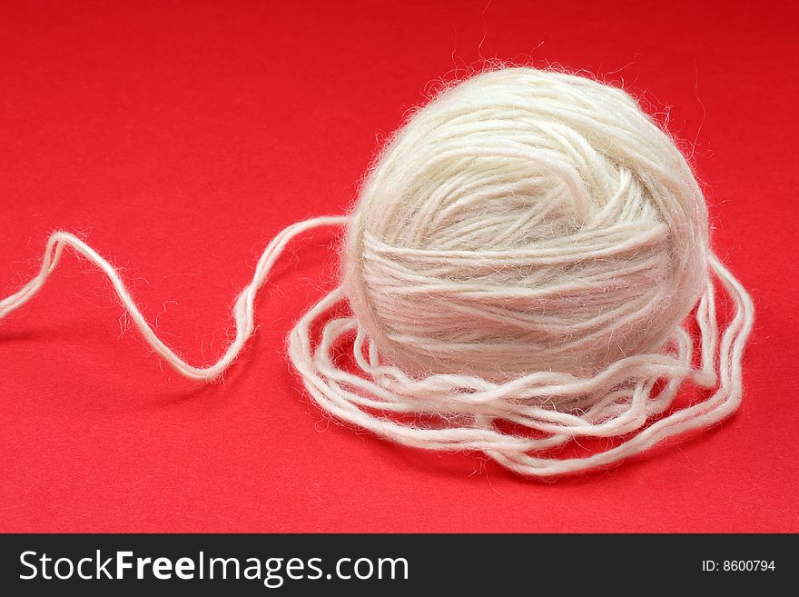 Ball of white wool on a red background