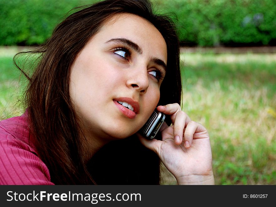 Pretty teenage girl on cellphone in the park