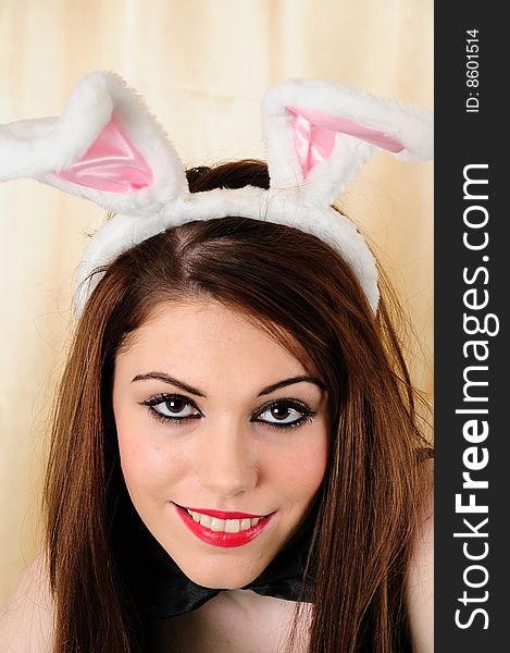 Female model straing in to the camera wearing a bunny rabbit head band with lush make up on and a bow tie against a golden back ground. Female model straing in to the camera wearing a bunny rabbit head band with lush make up on and a bow tie against a golden back ground
