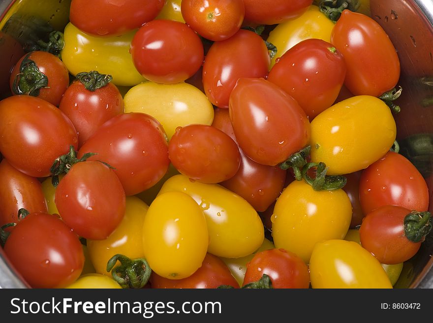 Two colours of tomatoes--red and yellow, are in the metal basin. Quite beautiful.