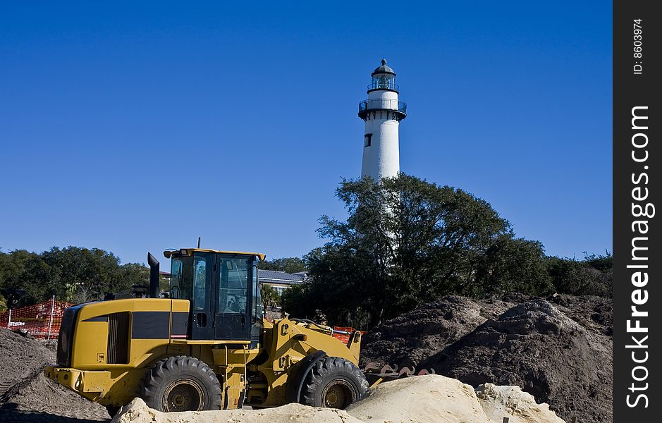 Heavy Construction Equipment with gravel and sand in front of lighthose. Heavy Construction Equipment with gravel and sand in front of lighthose