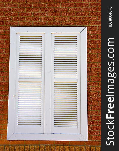 WhiteLouvered window on a red brick wall. WhiteLouvered window on a red brick wall