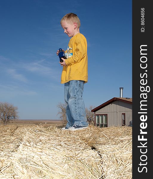 A color image of a young boy standing on a hay pile. A color image of a young boy standing on a hay pile.