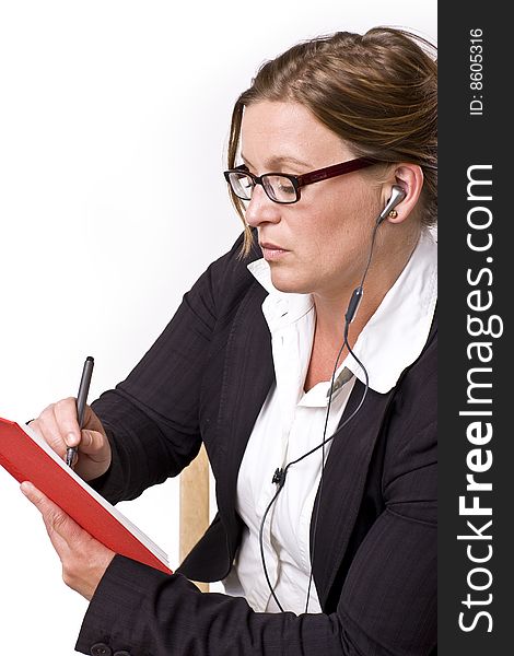 Businesswoman taking notes in a red notebook and handsfree