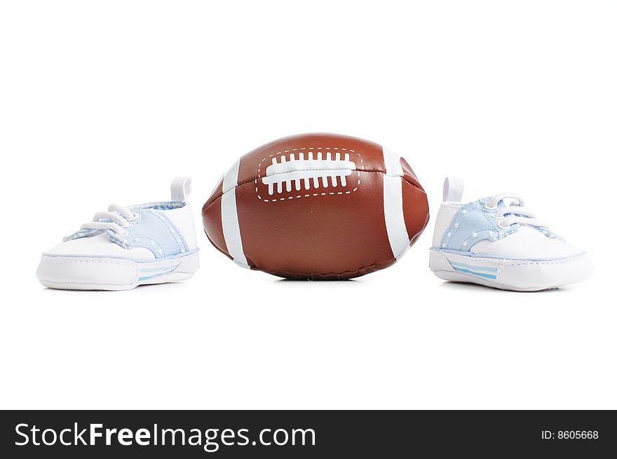 Football with baby shoes against a white background.