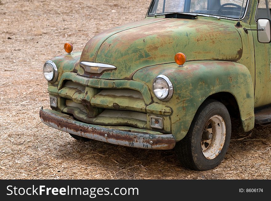 A close-up on an old rusty Chevrolet covered with chipped green paint. Cropped. The file contains an embedded clipping path. A close-up on an old rusty Chevrolet covered with chipped green paint. Cropped. The file contains an embedded clipping path.