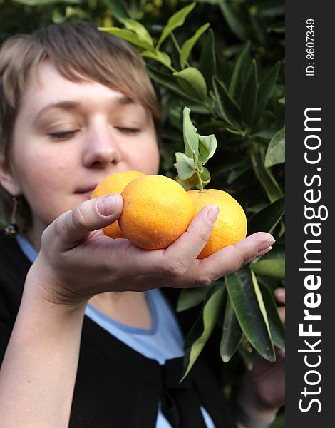 A girl smells ripe orange in orchard