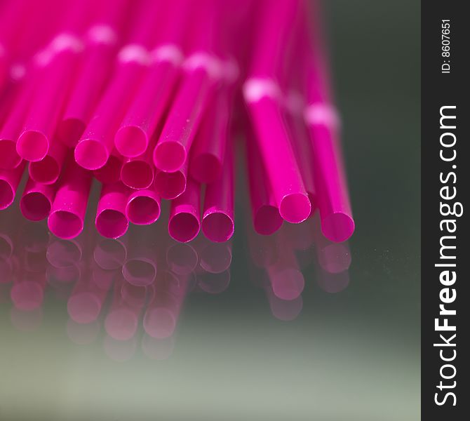 Pink straws on reflective surface