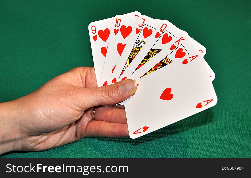 Hearts poker in women's hand, in front of green playing table