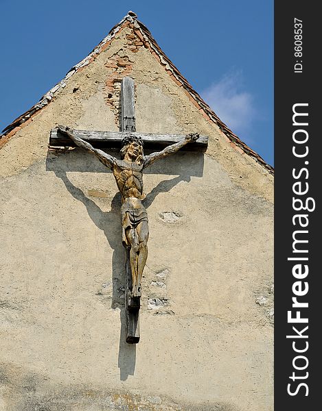 Wooden cross with sculpted jesus on a building