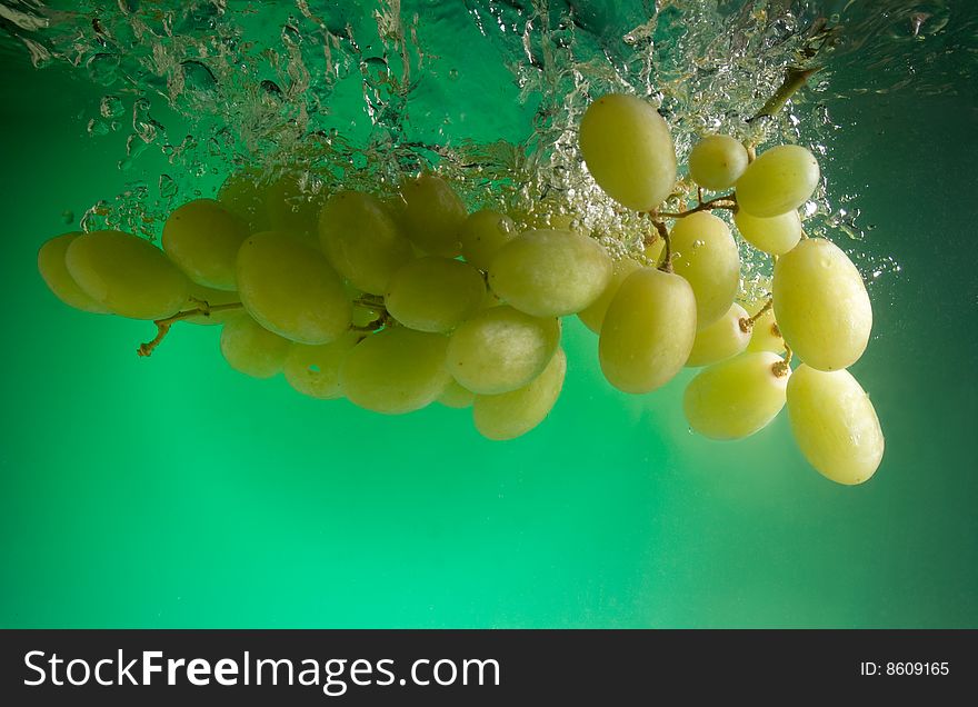 Grapes in water on a green background