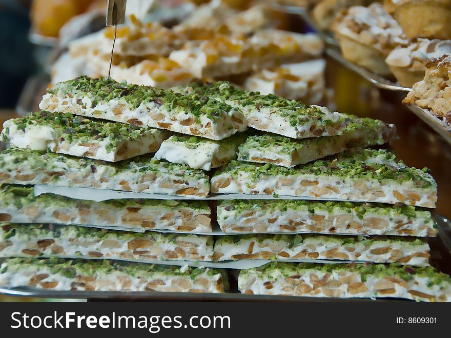 An traditional Italian nougat dessert made with pistachios and almonds in a window of a bakery. An traditional Italian nougat dessert made with pistachios and almonds in a window of a bakery.