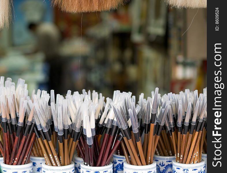 Brand new Chinese paint brushes protected with plastic covers on sale in porcelain jars
