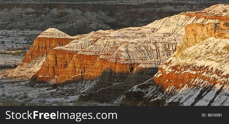 Morning sunlight falls upon snow laden red sandstone bluffs in Escalante park in southern Utah. Morning sunlight falls upon snow laden red sandstone bluffs in Escalante park in southern Utah