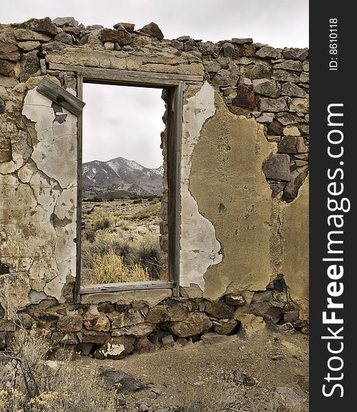 An old wall from a mining ghost town in Utah forms a window to distant mountains. An old wall from a mining ghost town in Utah forms a window to distant mountains