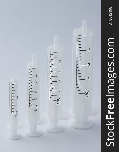 Four empty syringe barrels of increasing sizes - 2ml, 5ml, 10ml and 20ml