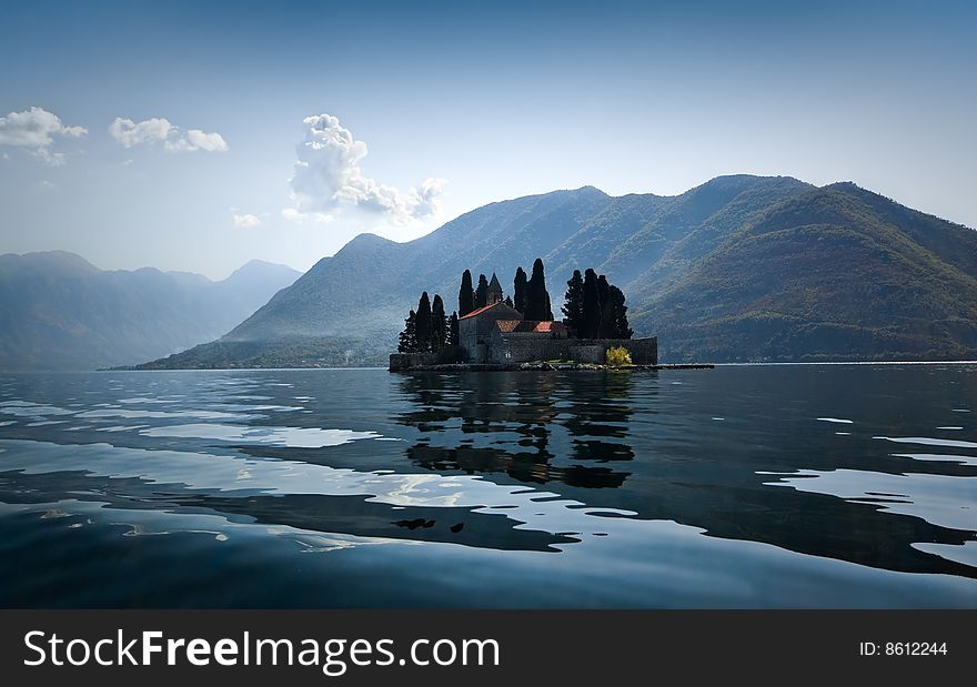 Natural island in Kotor Bay (Montenegro) with a Catholic monastery of St.George. Bright sunny day, mountains in light blue mist on the background