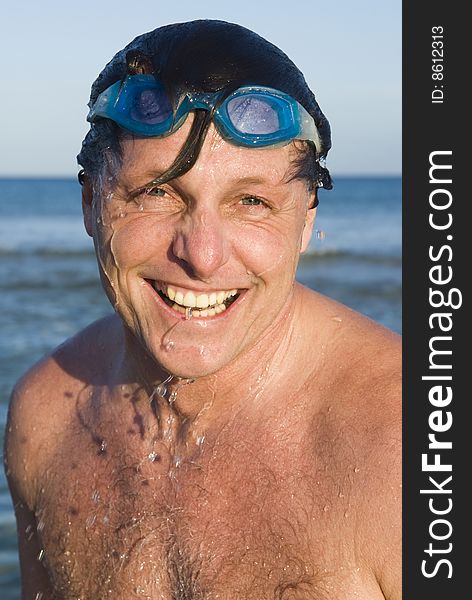 A portrait of a happy laughing forties man wearing swimming goggles with water dripping down his face. A portrait of a happy laughing forties man wearing swimming goggles with water dripping down his face.