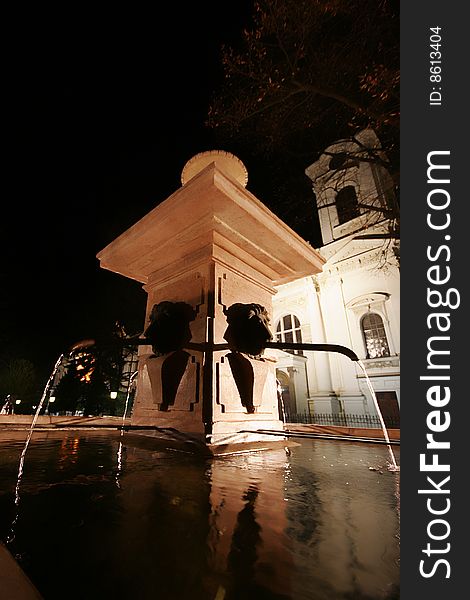 Fountain by night in sremski karlovci city in serbia with church in background