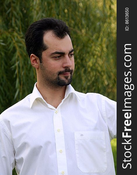 A man in white shirt with the serious look on the green leaves background