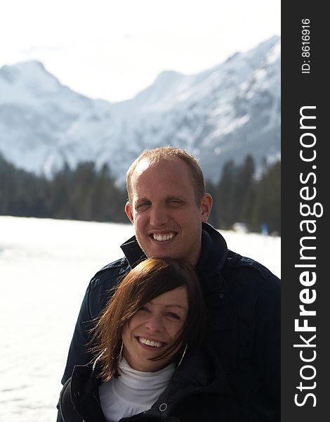 A young couple outdoor in a winter setting. The couple is hugging each other. A young couple outdoor in a winter setting. The couple is hugging each other.