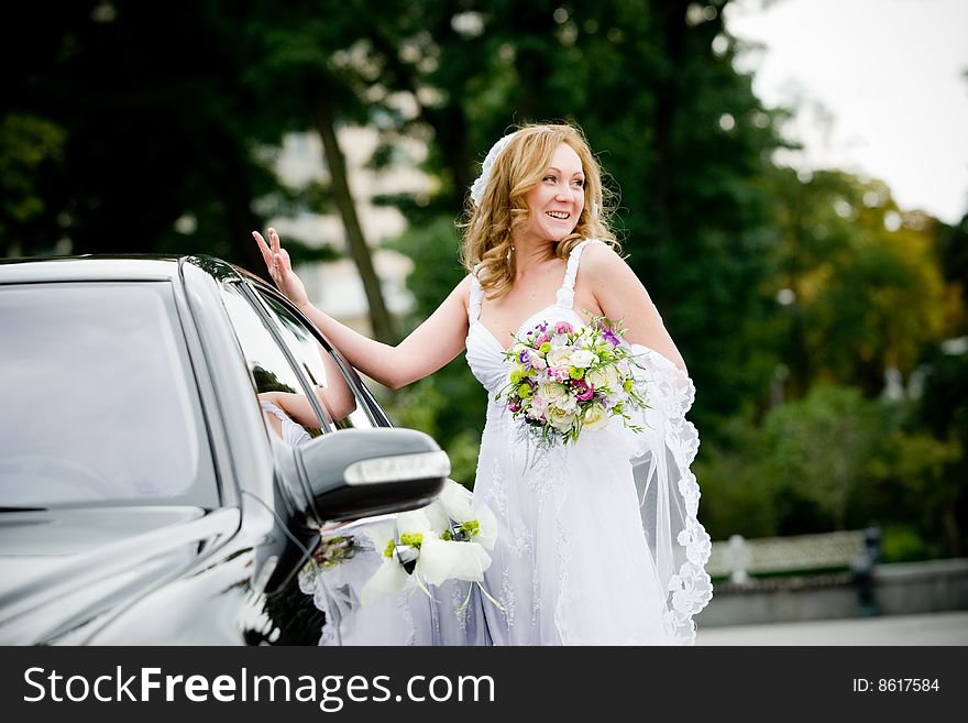 On the image there is bride. She is near car. On the image there is bride. She is near car.